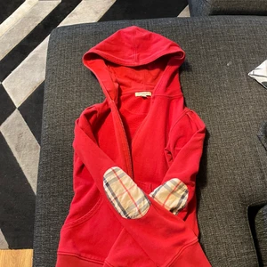 Burberry Zip Hoodie  - Jag säljer en röd Burberry zip Hoodie. Storlek S junior. För mer bilder kom dm.  Koftan är äkta. 
