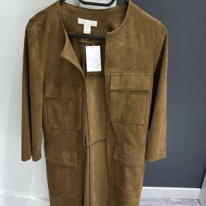 Jacka - Lätt jacka i mocka material från H&M aldrig använd i kanel färg. 3/4 i armarna. Storlek är 32 men kan passa även som 34 om man är inte så stor. 