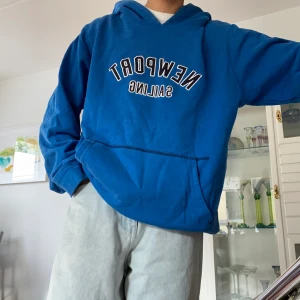 Blå Hoodie med tryck - Blå hoodie med tryck. Är tyvärr lite sliten med små hål (se bild 3). Ett litet där fram, sedan ett på ärmen. Den har även en liten skråma nere vid mudden samt vid luvan. Det är bara att höra av sig vid fler frågor eller om man vill ha fler bilder🫶🏼