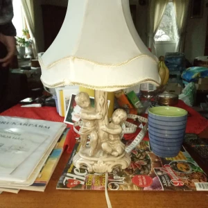 Bords/fönsterlampa med porslinsfot och vit skärm . - Fin bords/fönsterlampa med porslinsfot och vit skärm och fullt fungerande .hämtas i Skene .Swissbetalning tillämpas alt kontant betalning . Lampan mäter 35 cm hög .
