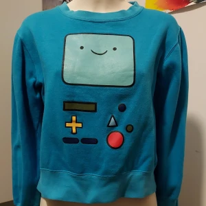 BMO sweatshirt, stl XS  - Gulligaste sweatshirten med BMO från Adventure Time på. Det gör lite ont att skiljas från den, men jag har dessvärre växt ur den sedan länge :c Eventuell frakt betalas av köparen 💙