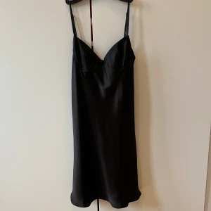 Svart klänning från zara - Svart klänning i satinliknande tyg, justerbara band & delvis öppen rygg! Kort i modellen! Köpt från zara i storlek xs! Aldrig använd med lappar kvar (köpt för 359 kr)!