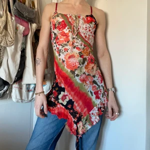 Vintage mesh topp klänning asymmetrisk blommig y2k orange rosa grön vit svart - Vintage stretchig blommigt mönstrad topp/klänning i mesh med asymmetrisk nederkant i orange, röd, rosa, vit, grön och svart 🍒🍑🍉🍊🍎 Så tidigt 2000-tal och har även justerbara axelband och knytning över bröstet! Påminner om nått rakt ut Gilmore Girls! <3