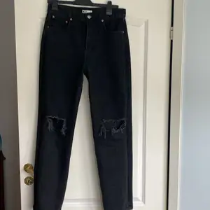 Lite pösiga jeans med hål vid knän som är i storlek 40