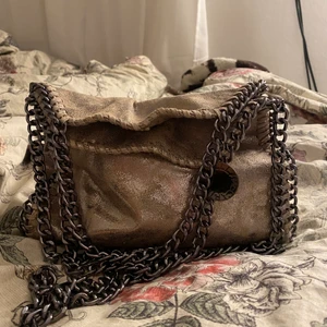 Stella McCartney liknande väska - Intressekoll på denna fina väskan som liknar stella McCartney väskorna (Köpt utomlands). Jättefin champagnefärg som skimrar. Endast använd ett par gånger så väskan är i nyskick. Skriv för fler bilder💕