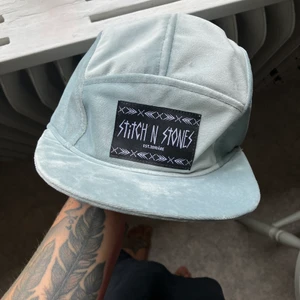 Stitch N Stones keps  - Ljusblå 5 panel keps i sammetstyg, handgjord av märket Stitch N Stones i Åre. Nypris 1200 kr. Har ett karborrespänne där bak så storleken går att justera! Aldrig använd! 400 kr eller bud. 