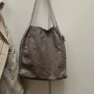 Tiamo väska - Trendig grå tiamo väska som jag köpt här på plick, är sönder lite vid dragkedjan men inget som man tänker på (lånade bilder)