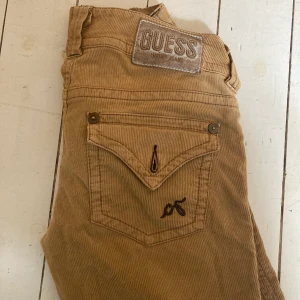  Bruna manchester byxor från Guess - Jättesnygga manchesterbyxor i ljusbrunt, från märket Guess. Lågmidjade och raka något vida ben nertill. Passar någon som är relativt kort (jag är runt 160). Saknar en knapp på bakfickan, annars i bra skick. 