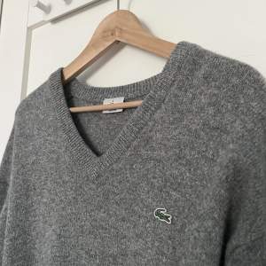 Grå, stickad tröja från Lacoste! Passformen är ganska oversized🤍