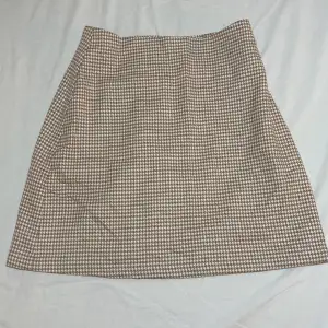 Vit-beigerutig kjol från Monki i storlek 24. Endast använd 2 gånger och i väldigt bra skick.