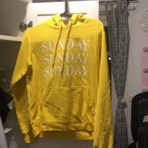 Gul Hoodie  - Storlek XS med texten ”Sunday” på framsidan 
