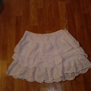 Vit kjol  - En kort kjol med fina volanger ganska skönt material funkar att ha när man går ut eller på en varm sommardag därimot finns det en liten rosa fläck vid dragkedja men inget man ser på långt håll men går säkert bort i tvätten 