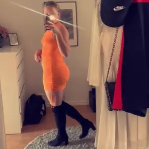 Orange klänning med knytning på sidorna. Går att justera längden själv. 