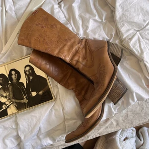 cowboy boots - äkta vintage, bruna cowboy läderboots köpt på en secondhand för ca ett år sedan men använd max 2 ggr, de förtjänar ett nytt hem! lite slitna på olika ställen, lädret på insidan av skon har flagnat (kan skicka bild). frakt går på 66kr! 🌟