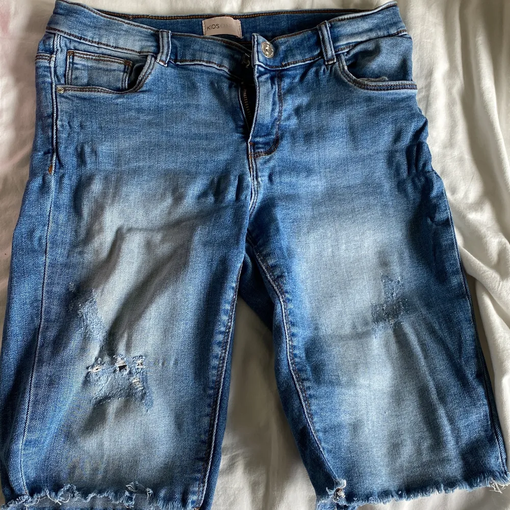 Det är ett par stretchiga och långa jeans shorts. Dem är Strl 158 i barnstorlek alltså passar både XS och XXS. Shortsen är i väldigt bra skick och är använd fåtal gånger. Jag säljer byxorna eftersom dem är för små för mig.. Shorts.
