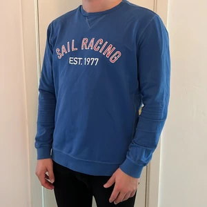 Sail Racing Sweatshirt Storlek XL - Blå sweatshirt med vit/röd broderad logga på framsidan. Fint skick. Jag är 190cm och tröjan har normal passform, varken slim eller oversize. Kan hämtas upp i Malmö eller skickas med spårbar frakt 66kr.