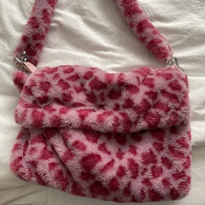 Rosa leopard väska - Leopardmönstrad väska i fuskpäls. Lagom stor. köptes för 200 säljes för 100. Mycket möjligt att priset sänks.