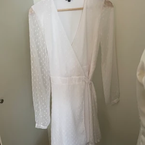 Vit klänning med knytdetalj  - Klänningen är i storlek 34. Ärmarna på klänningen är genomskinliga. Den har endast använts en gång. 