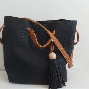 Större svart väska med bruna band. Går att använda som ett långt band eller två mindre axelnand. Aldeig använd. Priset är exklusive fraktavgift.