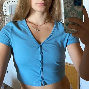 Topp med knappar framtill - Blå topp med knappar framtill som går att knäppa upp. Stretchig och skön, använd en gång så i skick som ny! Fraktar om köparen står för frakten, möjlighet till paketpris 