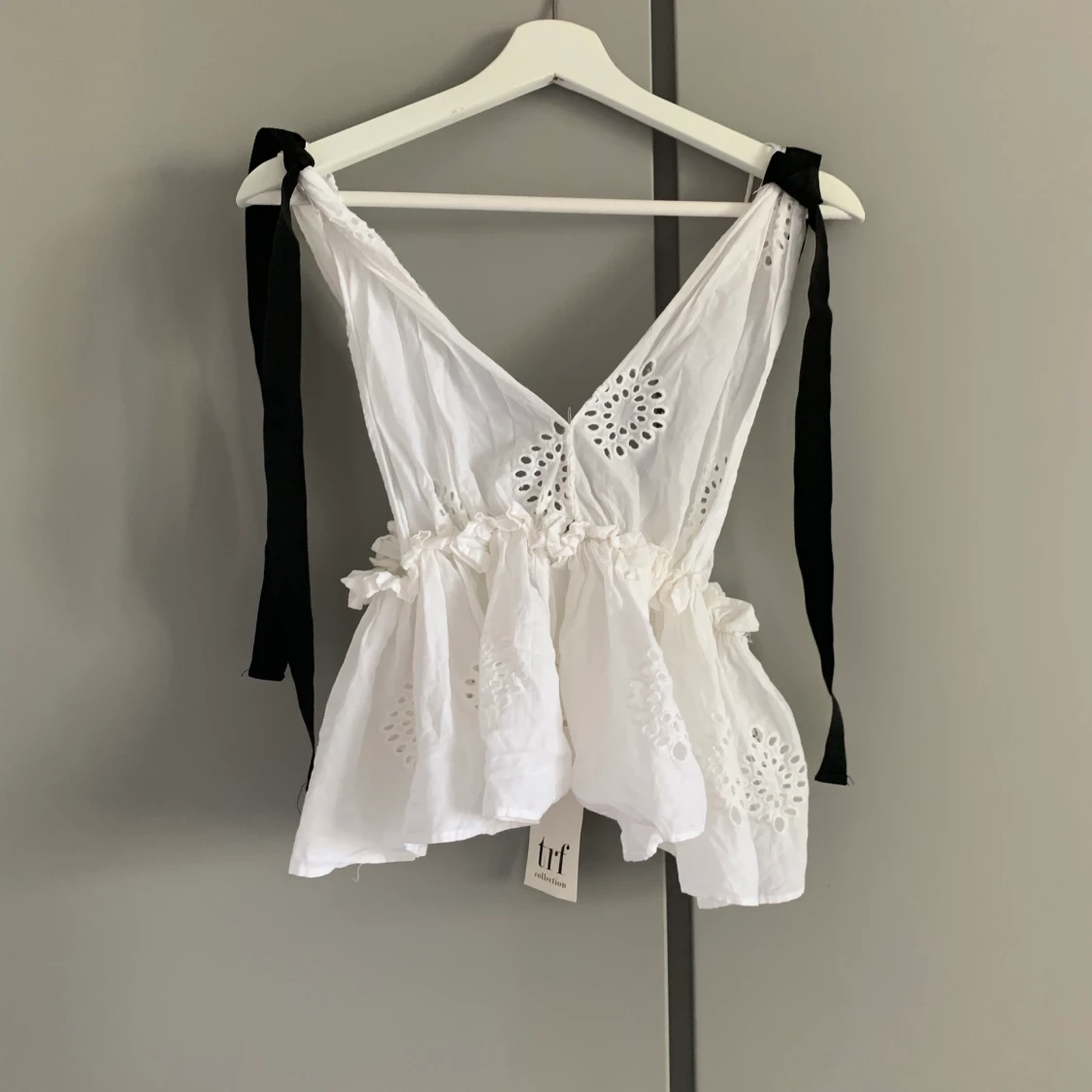 Vit topp med rosetter vid axlarna