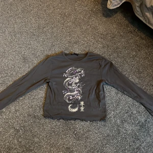 Storlek M - Mörkgrå långärmad topp med lila tryck på.