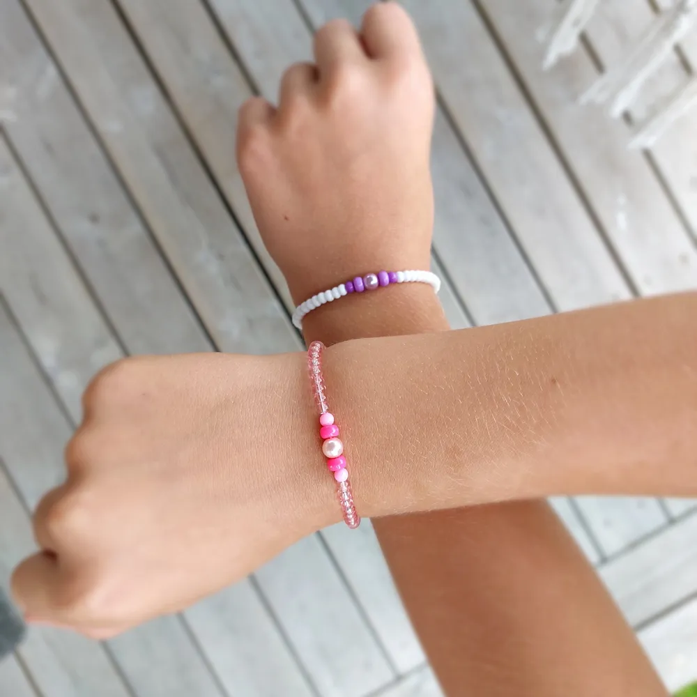 Två hemma gjorda armband som man kan ha som kompisarmband det får man bestämma själv. Ett armband är lila och vit och ett är rosa.. Övrigt.