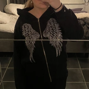 Svart zip hoodie - Svart zip hoodie, trendig med diamanter efterliknande två vingar