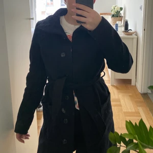 Marinblå kappa - Superfin marinblå kappa med bälte i midjan och hög hals!😊 Skulle säga att den passar storlek 32-38 beroende på vilken passform man är ute efter!