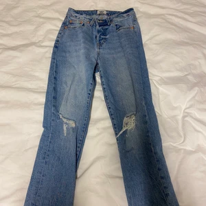 Jeans  - Ett par blåa jeans med hål vid knäna, storlek 36 