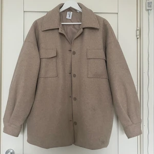 Beige kappa  - Beige oversized kappa från Collusion i storlek 34. I fint skick använd fåtal gånger. Köparen står för frakten!