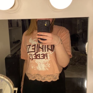 Söt-cool t-shirt - En lite bredare variant av t-shirt i rosa färg med tryck på och spetsvolang nedtill. Cool. 30kr+frakt