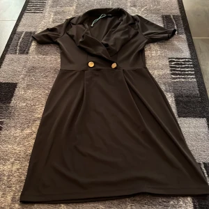 Svart klänning  - Är en storlek s, men kors vid bröstet. Och knappar på magen. Den går till knäna. 