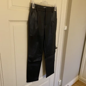 Skinnbyxor från NA-KD  - Säljer ett par snygga skinnbrallor från NA-KD. I fint skick, som ny. En knapp framtill. Storlek 36. 100% polyester. 
