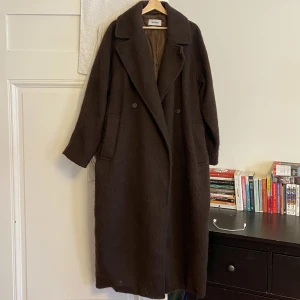 Weekday brun lång kappa, strl L - Tung superlång oversized kappa med bälte från weekday. Lurvig i materialet! Bara legat i garderoben så dags att hitta nytt hem. Nypris 1400. Köpare står för frakt.
