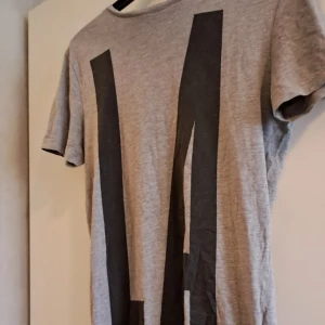 t-shirt  - En lite längre t-shirt dekorerad med dragkedjor på sidorna och tryck som funkar fint