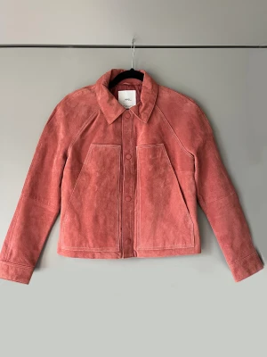 Rosa mockajacka vintage retro  - Mockajacka i rak modell. Tryckknappar och två fickor. Helfodrad. Knappt använd! Nyskick. Står storlek M men jag tycker den är lite liten. Skulle säga strl 36 Material: 100% läder  Strl: M/S Mått: bystvidd 96 cm, längd 54 cm