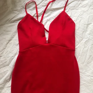 Klänning - Tight röd klänning med djup urringning och öppen rygg med korsade axelband. 