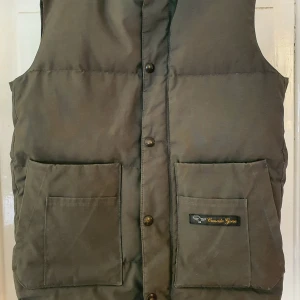 Canada Goose väst - Canada Goose vintage väst i mörkgrön färg. Fint skick, dock lite lätt blekt på sina ställen. Storlek XXS.