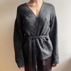 Gestuz ’Oba Mohair Wool Mix Short Belted Cardigan’ är en wrap tjocktröja utan knappar med fickor och bälte. Plagget är i fint skick. Köptes för 2300Kr. Säljer vidare för 1100Kr. 