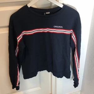 En mörkblå tröja - En mörkblå tröja med en text och en röd/vit rand. Andvänd ett par gånger men i bra skick. Frakt tillkommer 