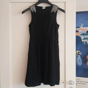 Klänning - Svart klänning i storlek S med pärlor på axlar, figursydd - nyskick 