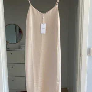 En beige fin Sommarklänning - En helt ny klänning från Vila. Köpt på salt i butik med endast 7 dagars öppet köp och bytesrätt vilket jag missade. Finns inne nu och kostar 350 kr. Säljer för en hundring billigare.