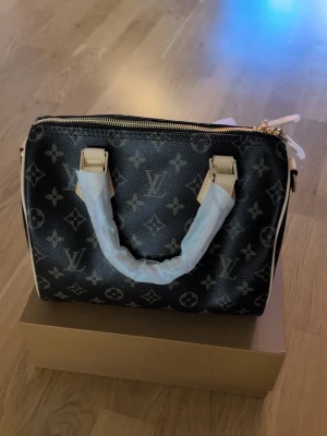 Speedy bag 25 - 👜 L*VSpeedy handväska ✨ 🔥 En av våra bästa kvaliteter på marknaden – mycket fin finish och detaljer. 🧵 Material: Canvas-liknande monogrammaterial med läderdetaljer ✨ Detaljer: Guldfärgade metalldetaljer 🎒 Medföljer: Axelrem + box/förpackning+ kvitto och certifikat  🏭 Skick: Helt ny, direkt från fabrik 📦 Förpackning: Packas noggrant och skyddat ⚠️ Viktigt: Denna väska är ej aut3ntisk ‼️. 