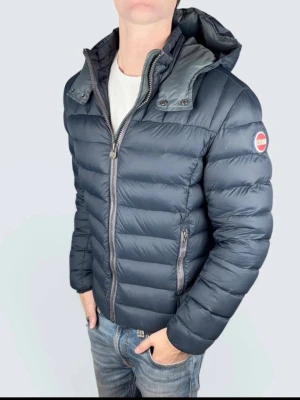 Colmar herr dunjacka med huva - Snygg och varm dunjacka från Colmar i mörkblått. Jackan har avtagbar huva, två sidofickor med dragkedja och Colmar-logga på ärmen. Storlek M (48) Nypris 5000, skriv om du har nån fundering:) billigare vid snabb och smidig affär