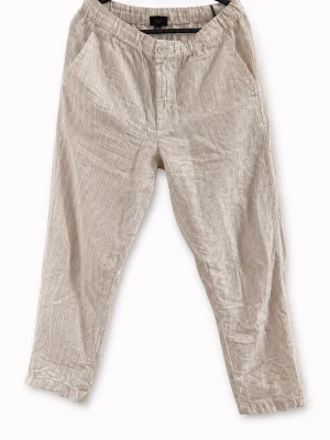 H&M Regular Fit randiga linnebyxor beige – XS - Snygga beige randiga byxor från H&M i Regular Fit. Storlek XS. Lätt och luftigt tyg med diskreta vita ränder, elastisk midja och avslappnad passform. Väldigt fina till vår/sommar och passar perfekt till en clean, minimalistisk eller skandinavisk stil. Fint begagnat skick.