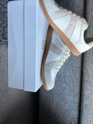Vita sneakers med beige detaljer - Stilrena sneakers i vitt med beige mockadetaljer och gummisula. Skorna har vita och beige partier i läder och mocka, samt beige snören. Klassisk och clean design som passar till det mesta.