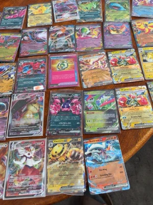 Stor samling Pokémonkort GX/EX/V - Säljer en stor samling Pokémonkort med blandade GX, EX och V-kort. Flera kort har holografiska effekter och färgstarka illustrationer. Korten är skyddade i plastfickor och inkluderar både Pokémon och tränarkort från olika serier. Perfekt för samlare eller Pokémonfans! Kan diskutera priset