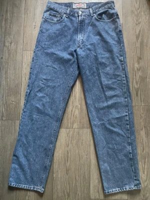 Blå raka jeans med hög midja - Klassiska blå jeans i rak modell med hög midja och fem fickor. Jeansen har en ljus tvätt och är tillverkade i denim. Passar perfekt till en avslappnad stil och har en vintagekänsla.