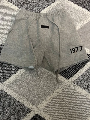 Essentials shorts - Säljer mina Essentials-shorts i färgen Dark Oatmeal. Sparsamt använda och i superbra skick.Det finns ett litet märke till vänster om trycket (se bild), men det syns knappt alls när man har på sig dem. Annars helt felfria och fräscha. Skickar snabbt!